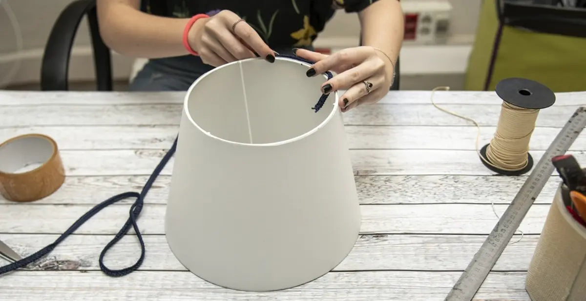 Hands of a woman measureing a lampshade on a white table