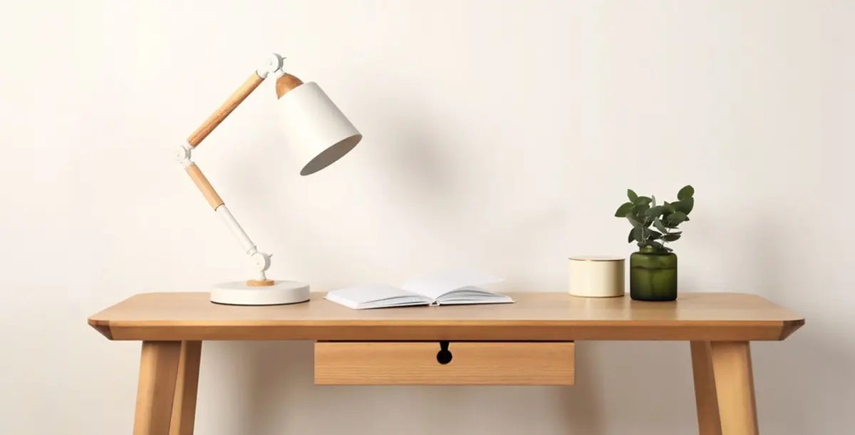 Stylish modern desk lamp and plant on wooden table near white wall