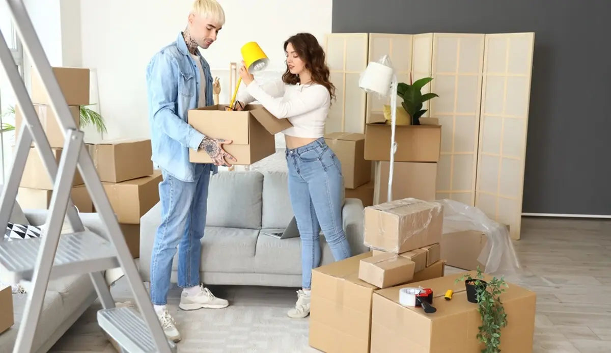 Young couple packing lamp in room on moving day