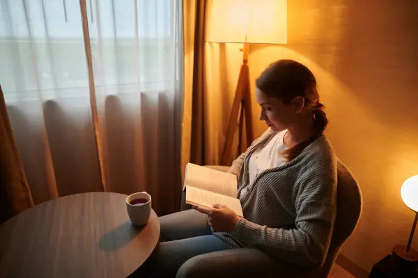 oung woman reading under floor lamp